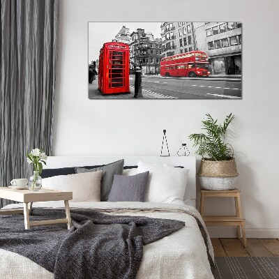 Foto op glas Een rode telefoon in een grijze stad